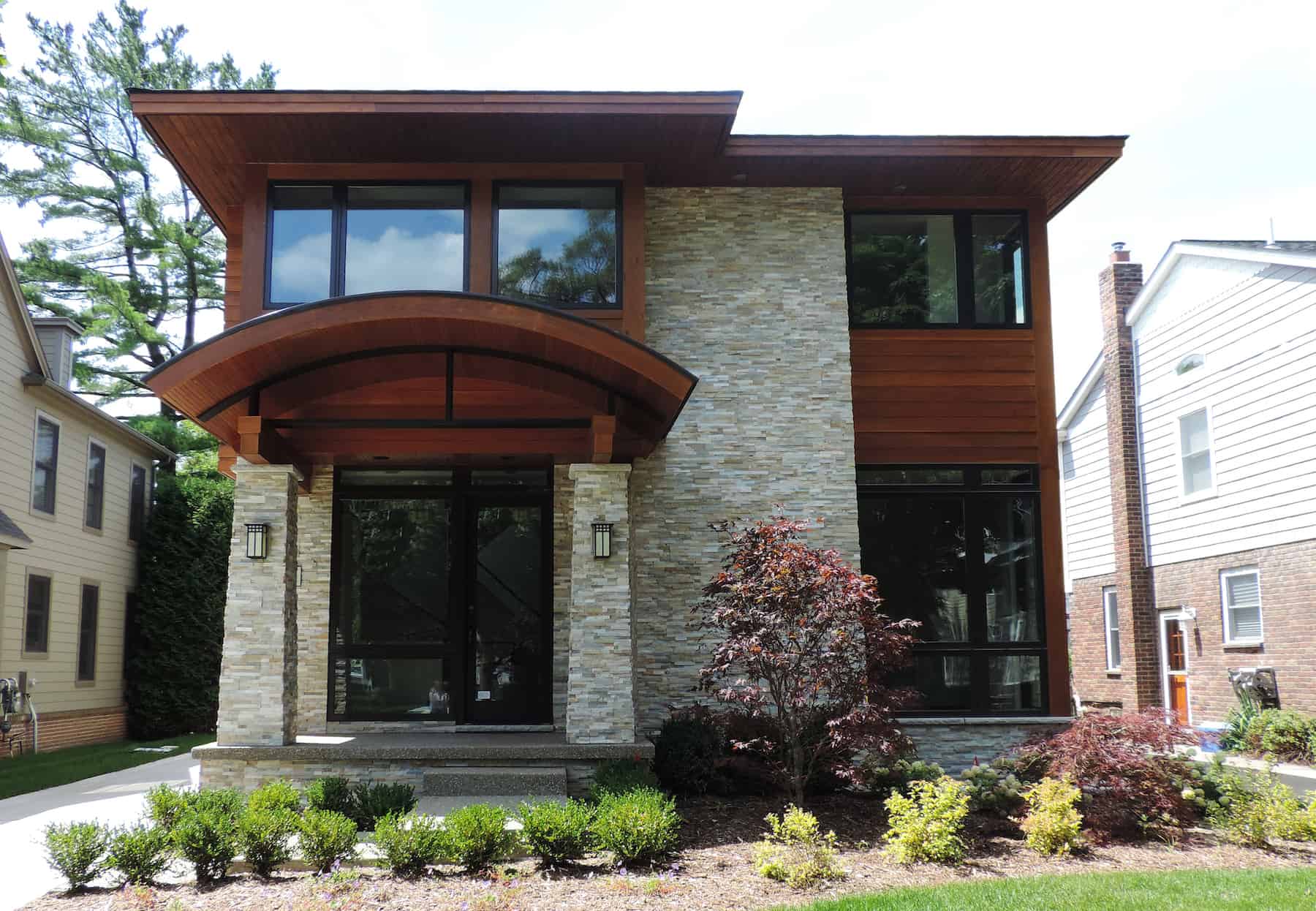 Natural stone veneer and wood home exterior in a modern style with arched details