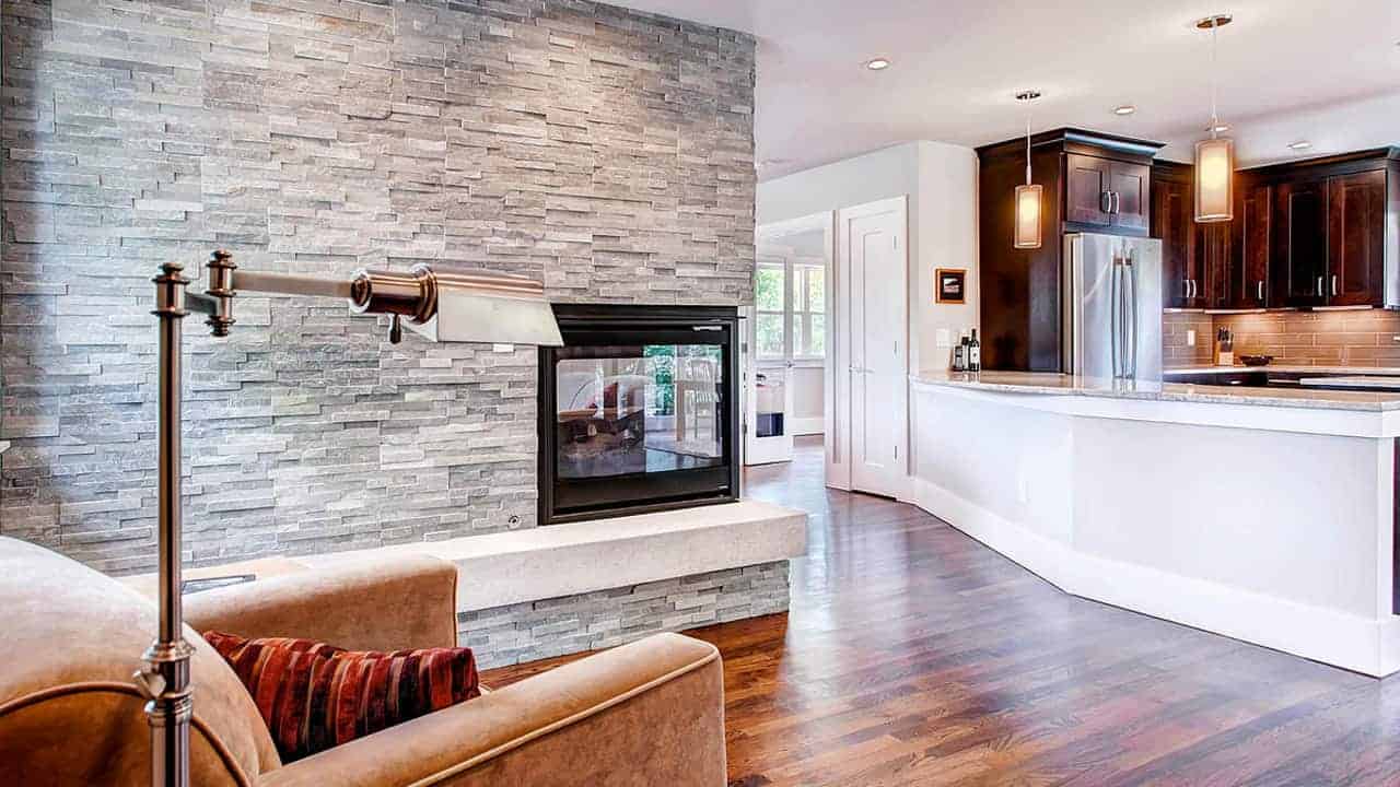 Multi-sided fireplace wrapped in textured natural stone veneer