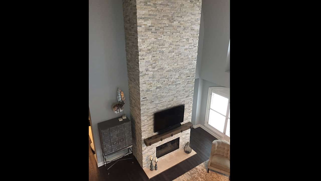 Floor-to-ceiling stone veneer fireplace beneath a vaulted ceiling