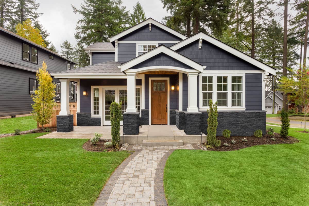 craftsman style home with dark grey stone exterior with natural stone veneer on lower part and on columns