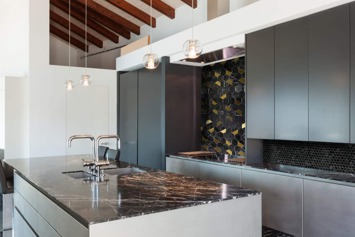 Black Marble and Brass Hexagon tile on a kitchen backsplash with black marble penny round tile in a modern upscale kitchen