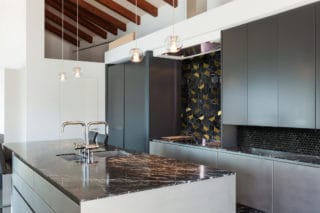 Black Marble and Brass Hexagon tile on a kitchen backsplash with black marble penny round tile in a modern upscale kitchen