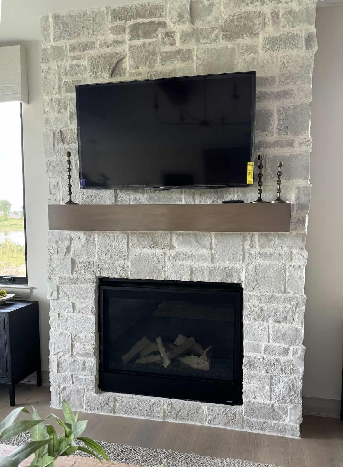 large format light colored rustic stone on a fireplace with a tv and mantle