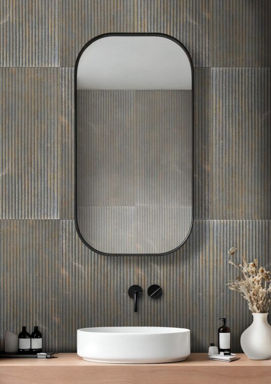 minimalist modern fluted natural stone tile bathroom with white sink bronze fixtures and rounded mirror