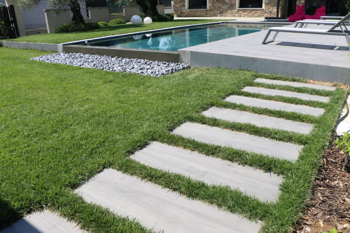 Darker wood looking outdoor porcelain pavers that are designed look like classic wood, while offering the properties of porcelain, set up for an outdoor patio and walkway