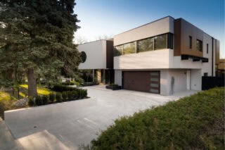 A white, cream, and beige colored outdoor porcelain paver set up as a driveway and outdoor area for a home