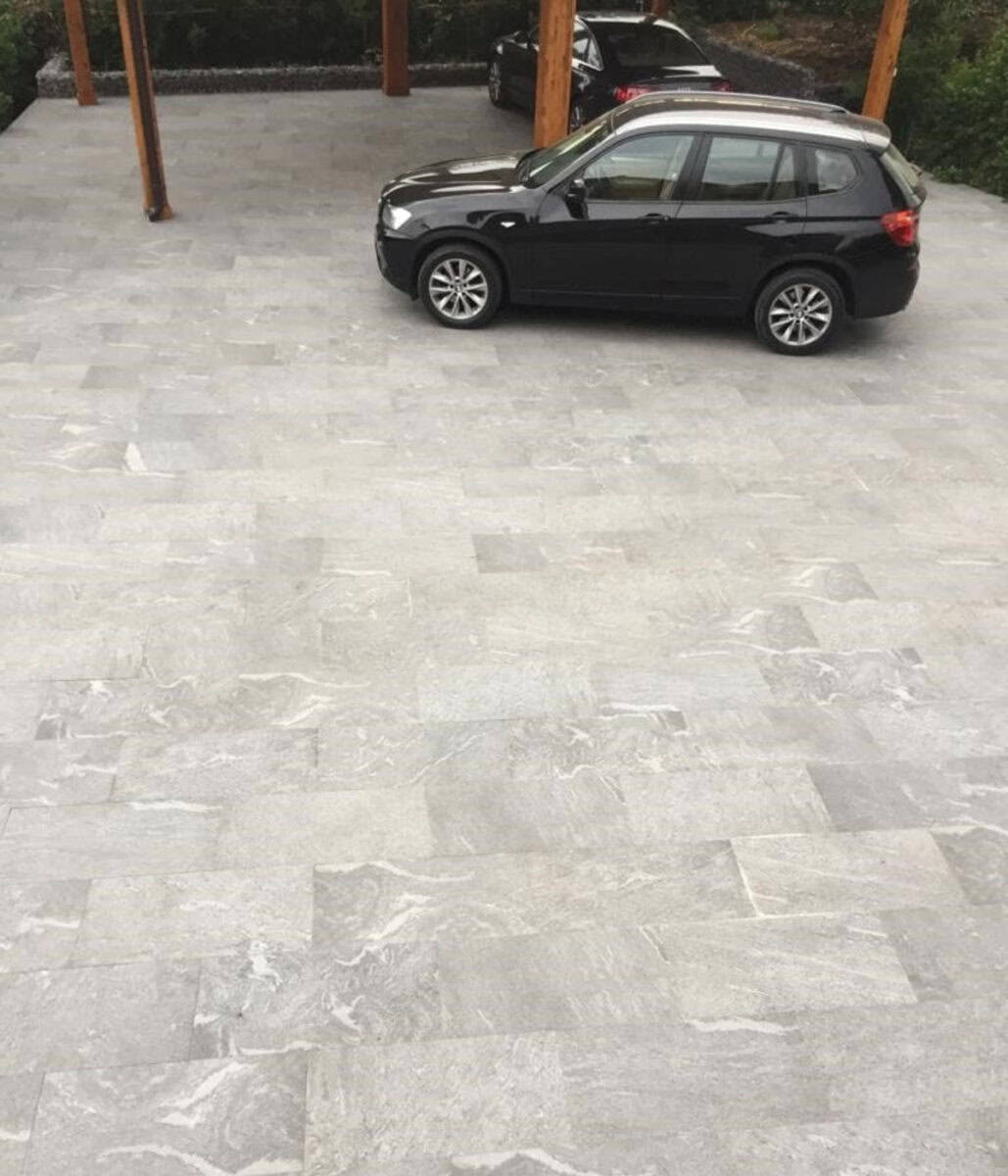 Heavily textured, gray to black outdoor porcelain pavers that have a premium look to a driveway set up.