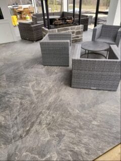 Earth-grey colored outdoor porcelain pavers laid out in patio format.