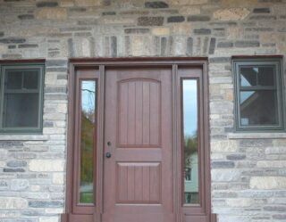 Split ledgestone face in Limestone in a blend of Brown, Grey, Tan, Black with horizontal veining set up for an entryway to a house