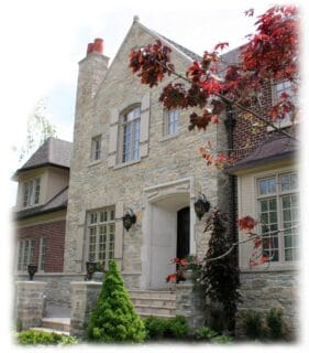 Stone veneer pieces of tumbled ledgestone and bed face stone made of Limestone in warm shades of tan on the exterior of a home